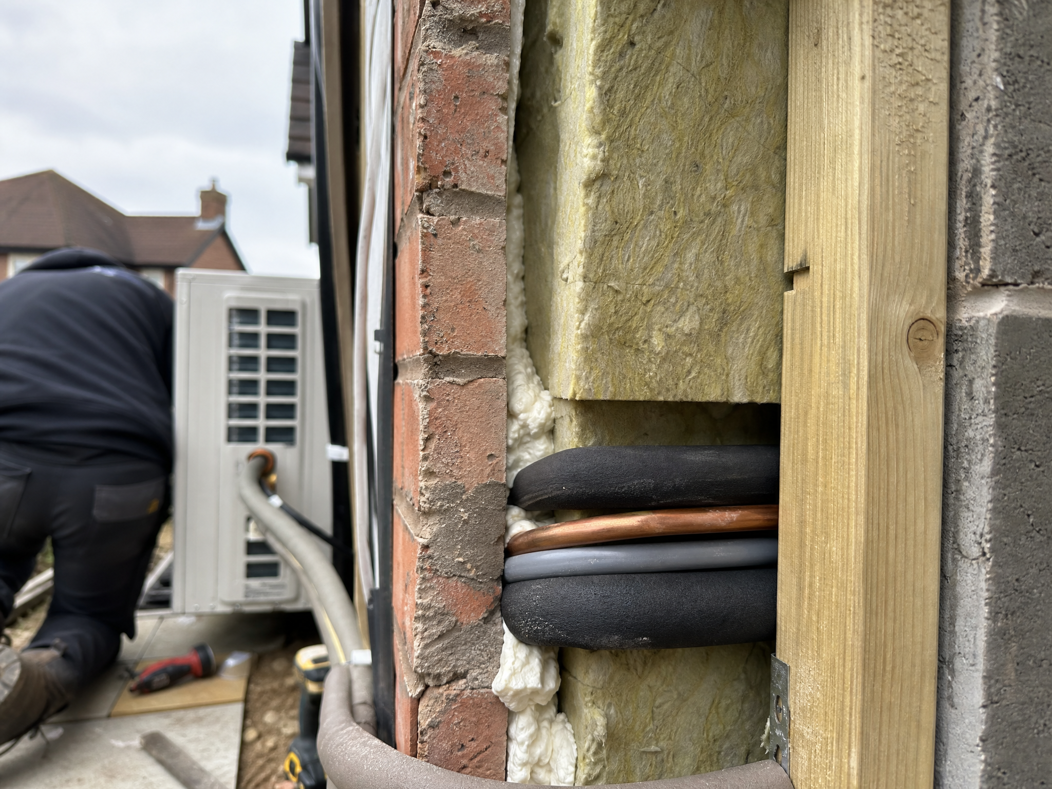 Close-up detail of materials and technique used in air source heat pump installation — showing quality
