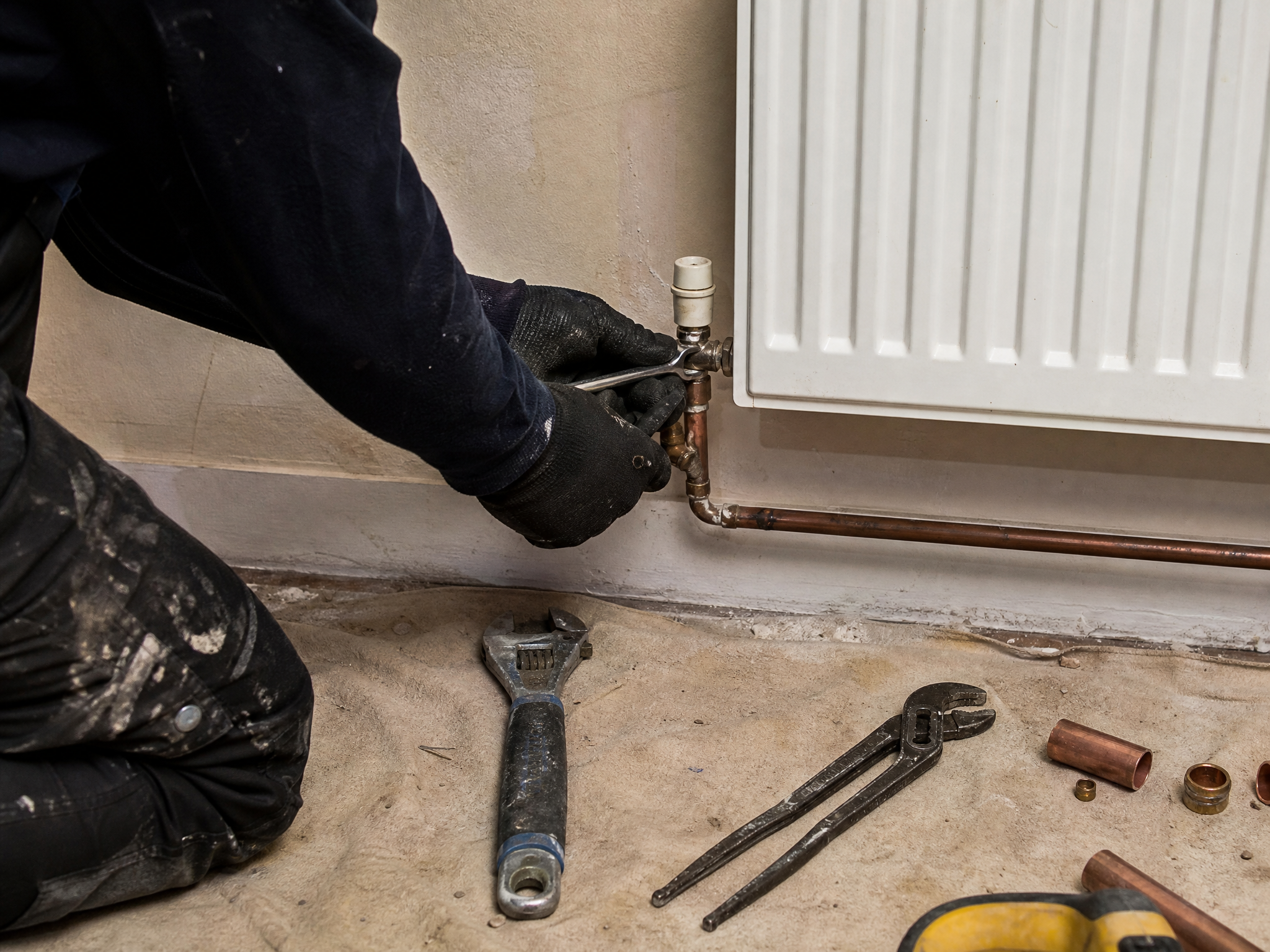 Professional installer carrying out radiator upgrades for heat pumps in a UK residential property